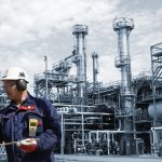 Two engineers in front of large refinery