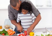 Dad helping son cut vegetables