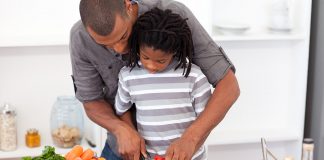 Dad helping son cut vegetables