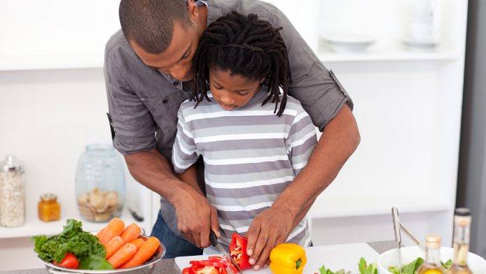 Dad helping son cut vegetables