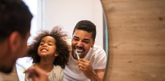 Dad showing daughter how to brush teeth