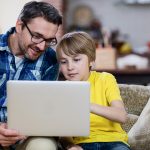 Father helping son on computer