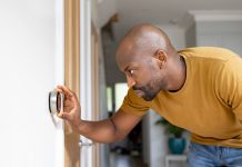 Man adjusting the temperature on the thermostat of his house